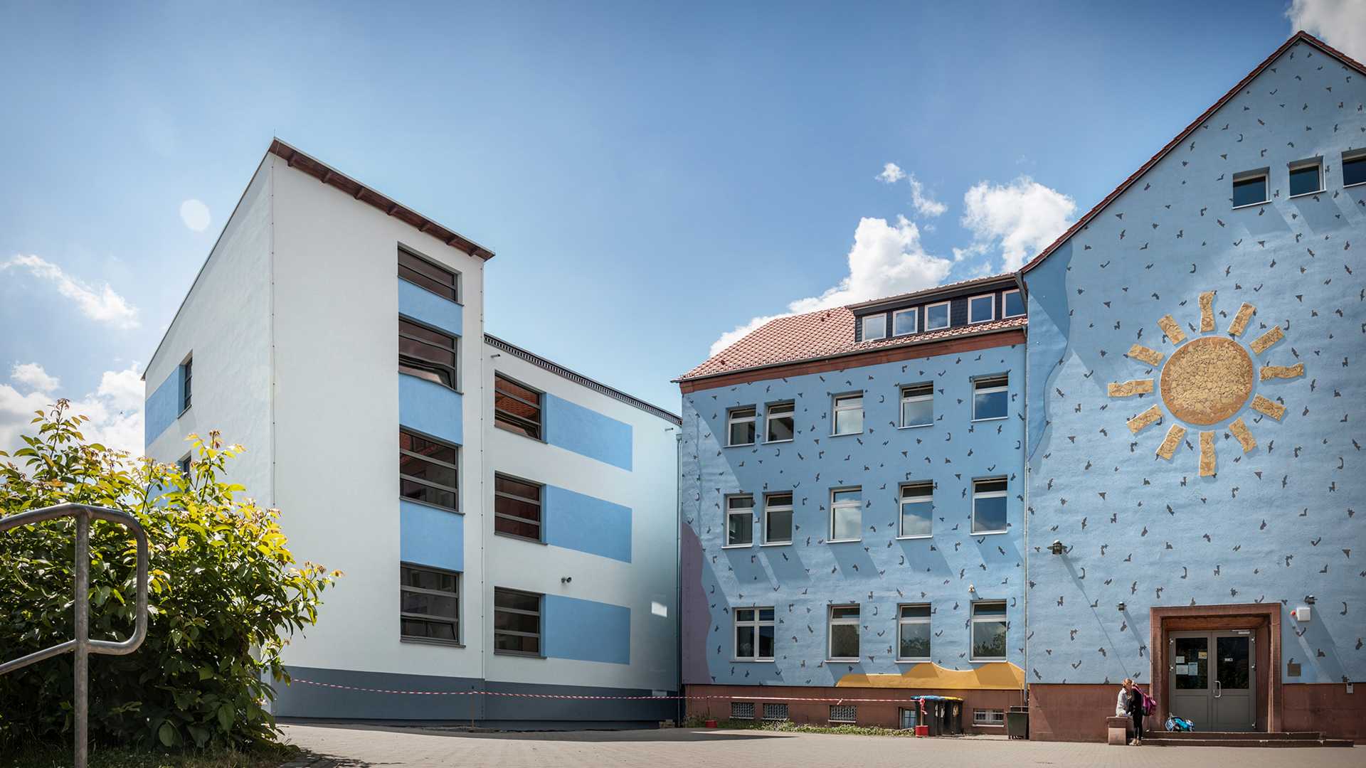 Schulzentrum Zwenkau, Außenansicht der blauen Wand mit aufgemalter Sonne